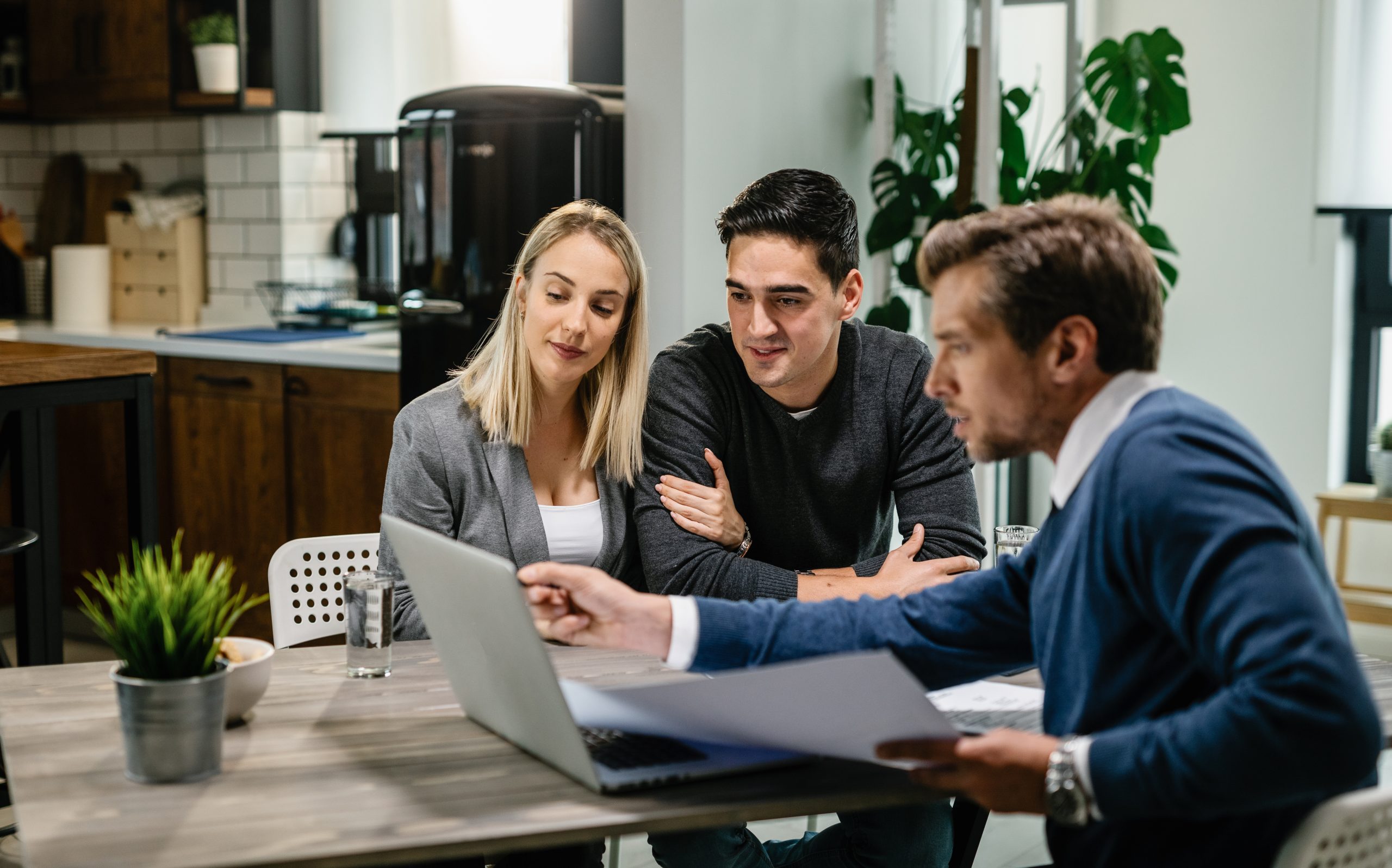 Smiling couple using a computer with their investment agent on a meeting